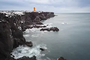 Orange lighthouse Ondverdarnes stands on a dark cliff