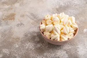 Orange and pink marshmallow in ceramic bowl on brown concrete background
