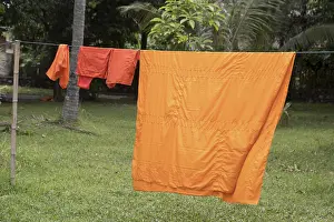 The orange robes of the Buddhist monks are dried on a rope in the Buddhist monastery