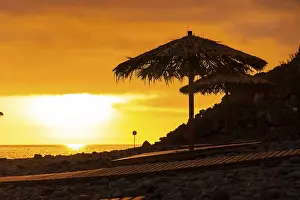 Orange sunset on the umbrellas at Ponta do Sol beach