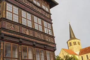 Ornamental half-timbered house next to an illuminated church tower