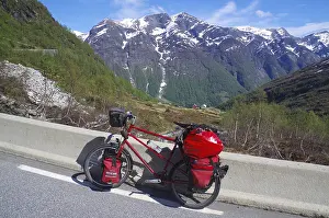 Packed bike on a road in front of snow-covered mountains