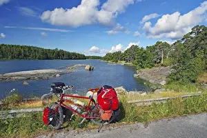 Category Scandinavia Prints: Packed, red touring bike on the shore of the Baltic Sea