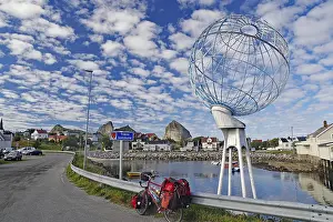 Packed touring bike in front of a huge globe and a harbour