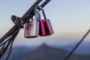 Two padlocks hanging on a metal rope with a mountain backdrop