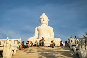 Pai, Thailand - Jan 2016: Group of people sitting next to white Buddha in Pai