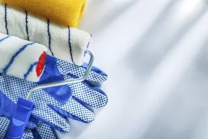 Pair of protective gloves paint rollers on white background