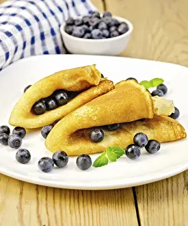 Two pancakes with blueberries and mint on a white plate