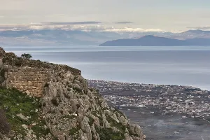 Panoramic view of a coastal town with sea and mountains in the background under a grey sky