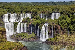 Panoramic view of lush waterfalls amidst dense vegetation