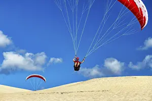 Two paragliders in flight, take-off on a dune