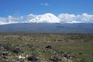 Peaceful landscape with snow-covered mountain and rocky plains under blue sky