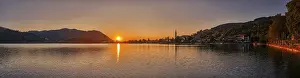 A peaceful sunset over a lake with mountains and a village in the background