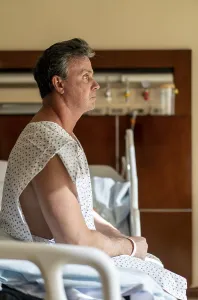Pensive patient sitting in hospital bed looking away