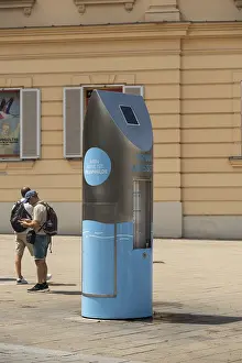 Two people in front of a drinking water fountain in the city centre of Vienna