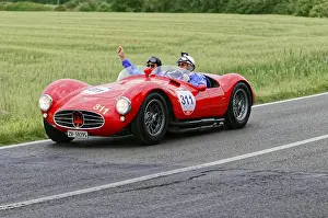 Two people joyfully driving a red Maserati on a country road