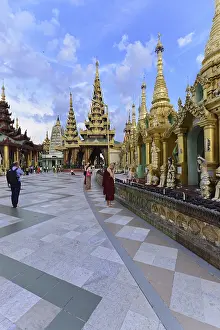 People and monks explore an impressive temple complex under clear skies