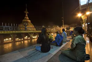 People praying in front of a golden rock and stupa