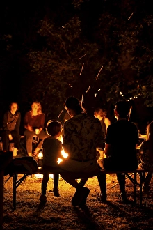 People sitting comfortably around a campfire in summer