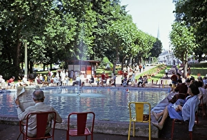 People sitting around a fountain and a boat pond, Aix les Bains, Savoie, France, 1974, Europe