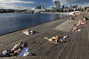 People sunbathe on a deck with a view of the Munch Museum in Oslo