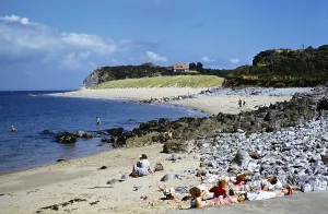People sunbathing on the beach at Priory Bay, Caldey Island, Pembrokeshire Wales, United Kingdom in the late 1950s