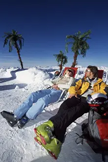 Two people in sunloungers in the montains in winter