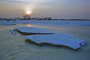 People walk across ice rink, sunset