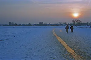 People walk across ice rink, sunset