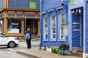 People walking past colorful buildings with quaint architectural details in Lunenburg