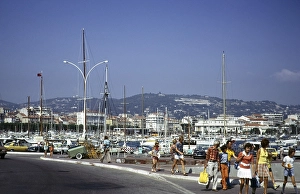 People walking past a harbour crowded with boats in Cannes, Cote d'Azur, France 1974