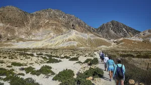 People walking on a path through a mountainous landscape under a clear sky