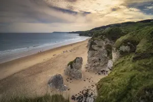 People walking on White Rocks Beach with limestone rock formations at sunset
