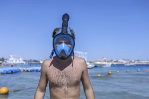 Person on a beach wearing a blue snorkel mask