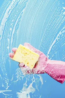 Person cleans glass with sponge on blue background