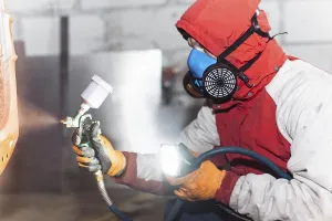 A person in protective gear using a spray gun