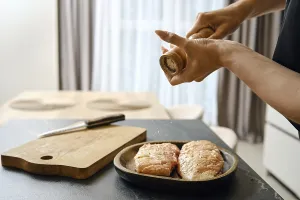 A person seasons fresh duck fillets with sea salt in a stylish kitchen