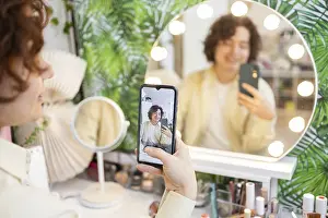 A person takes a selfie using a smartphone in front of a round