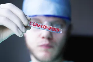 Person with test tube labeled COVID-2019