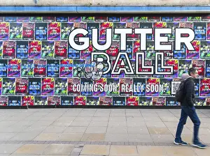 Person waking past posters on shopfront advertising Gutter Ball ten pin bowling attraction
