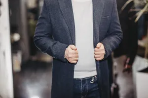 A person wearing a blazer over a white sweater and dark jeans