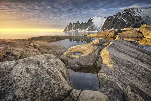 Person with yellow jacket standing on the rocky beach of Tungeneset