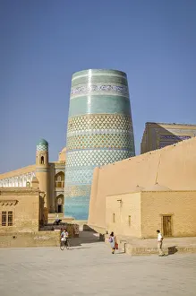 Photo of large circular tower with blue ornaments on its bricks in streets of Khiva