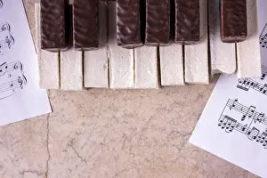 Piano lined with bitten off marshmallows on a beige background