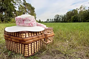 Picnic basket with straw hat, on green grass