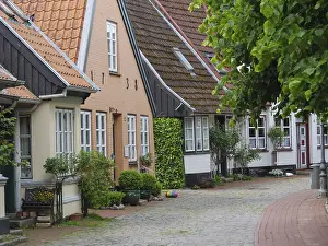 Picturesque half-timbered houses on a cobbled lane with many plants and decorations