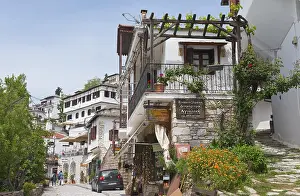 Picturesque view of a traditional Greek street with flowers and balconies under a blue sky