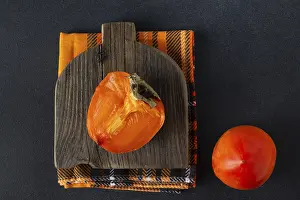 A piece of persimmon lies on a wooden board
