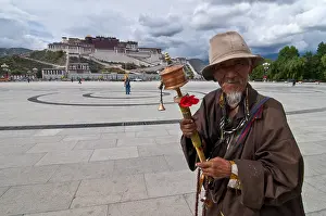 Pigrim with a prayer wheel in front of the Potala Palace