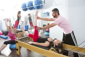 Pilates aerobic personal trainer instructor man in cadillac fitness woman exercise